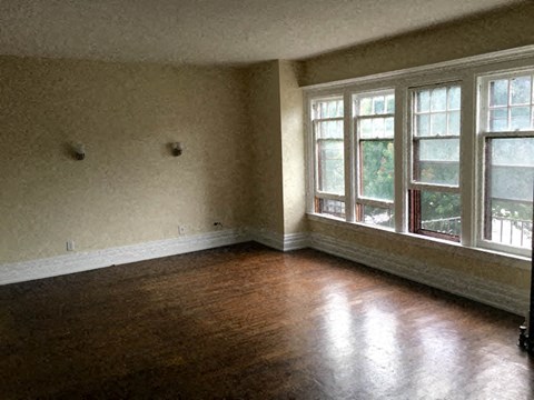 an empty room with a wooden floor and large windows